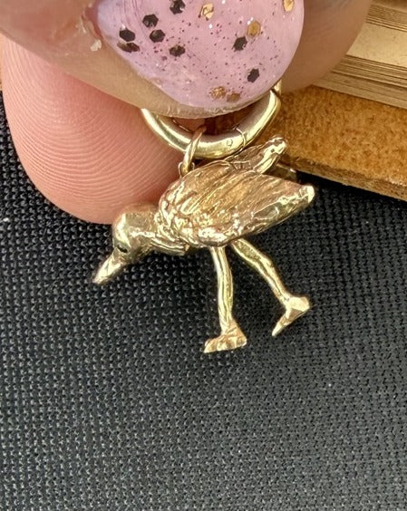 Back view — solid cast 14k gold piping plover, held for scale
