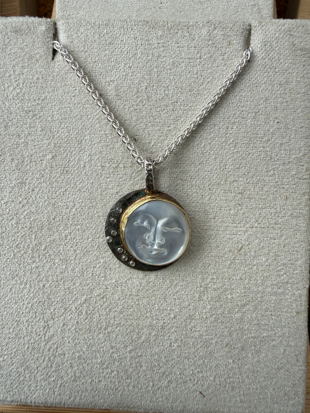 Mother of pearl moon face pendant in sterling silver with an 18k bezel and seven lab diamonds