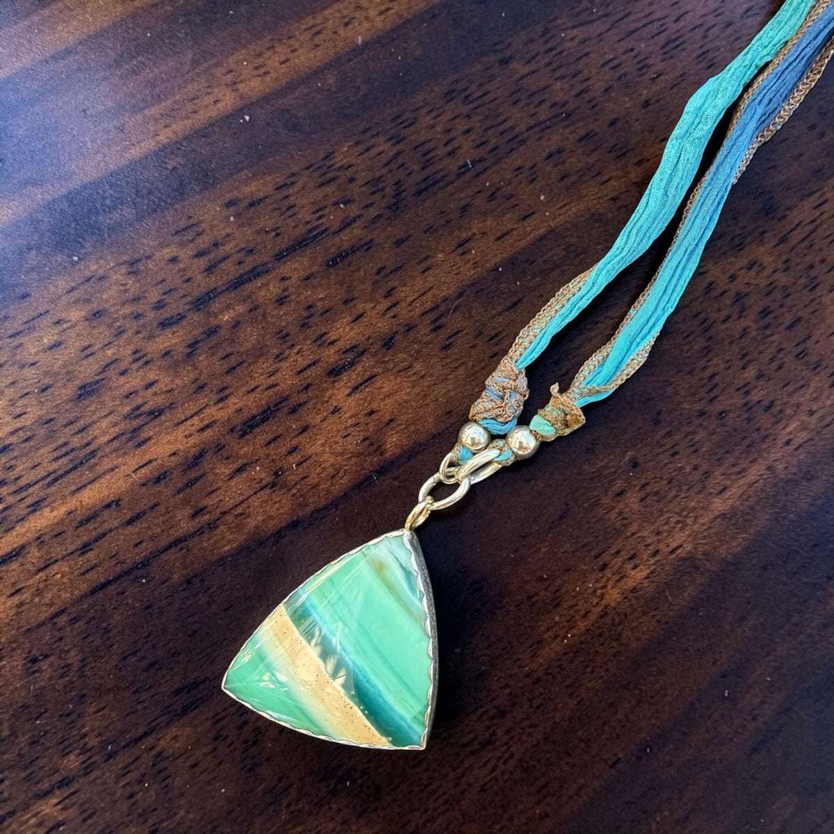 Opalized fossil wood pendant clipped onto the included 30-inch silk cord